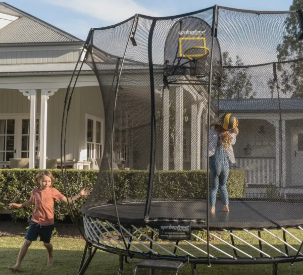 Děti skákající na trampolíně a muž házející míč